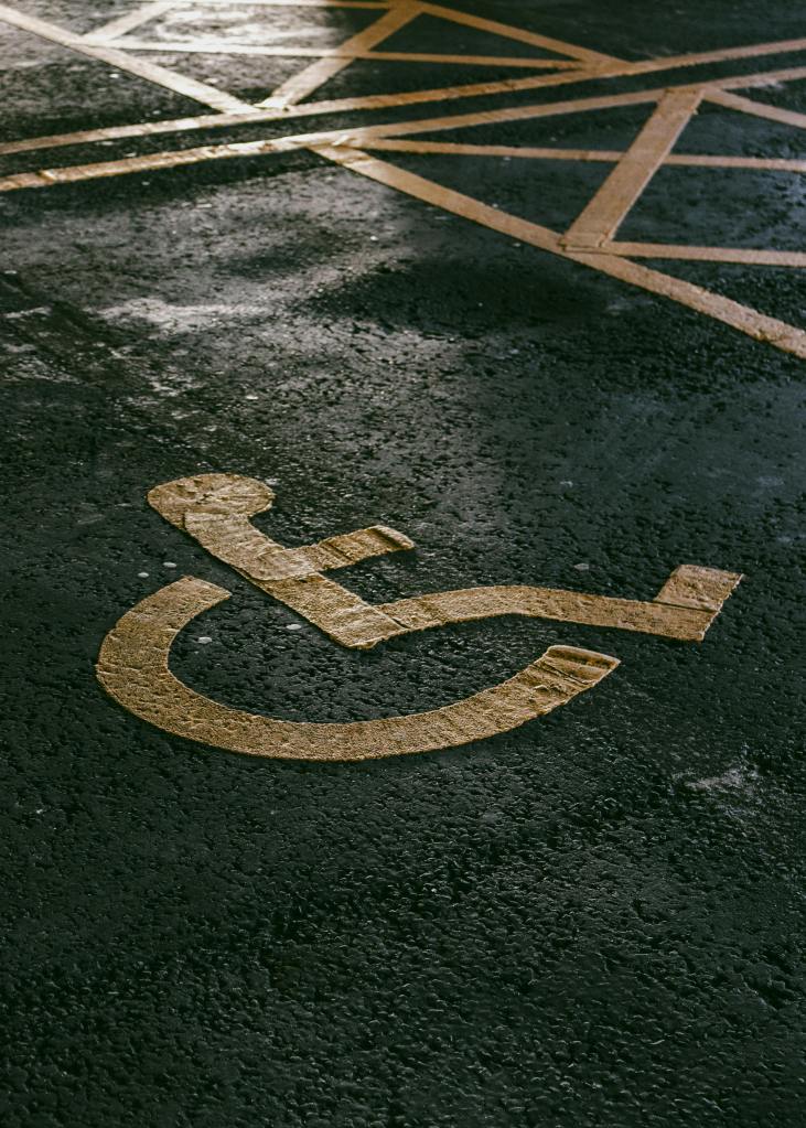 Accessible parking space marking with a wheelchair symbol painted on wet asphalt.
