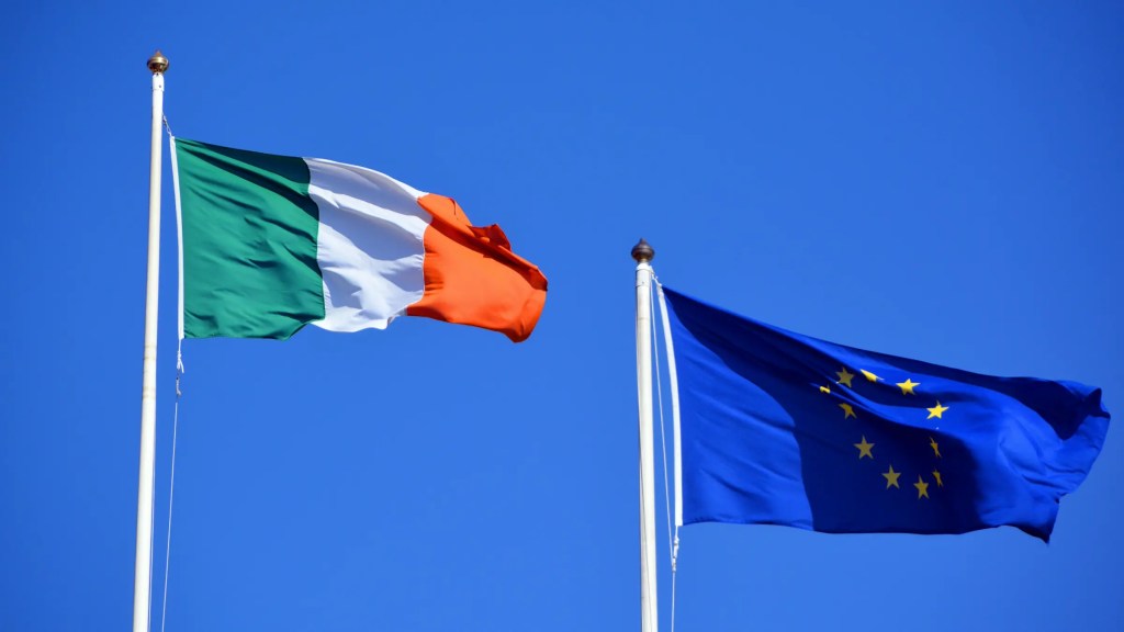 The Irish and European Union flags flying side by side against a clear blue sky.