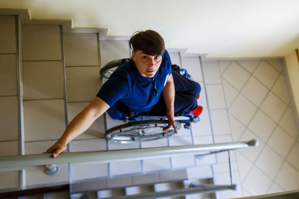 A wheelchair user facing a staircase inside a building, illustrating barriers to accessible housing.
Photo credit by Nadiia Doloh